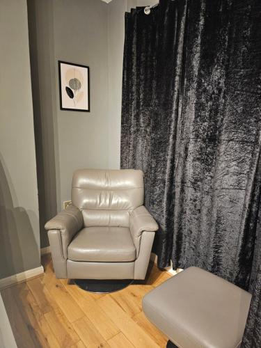 a leather reclining chair in front of a black curtain at Umbrella Properties London Woolwich in London