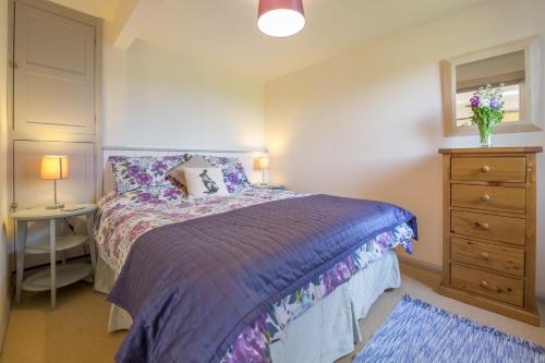 um quarto com uma cama com um edredão roxo em Foxglove 