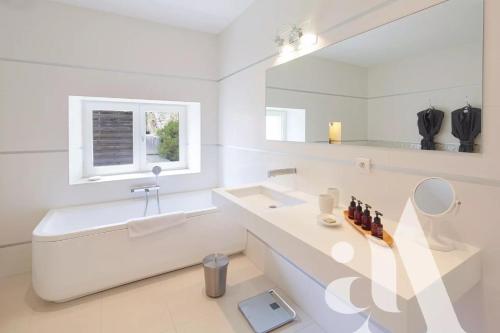 een witte badkamer met een wastafel en een spiegel bij Mas de L'Amarine in Saint-Rémy-de-Provence