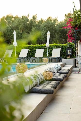 a row of chaise lounges and chairs next to a pool at Trianon Studios in Tsilivi