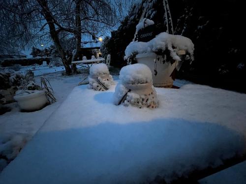 two snowmen sitting in the snow next to a fire hydrant at La Romance et la Romanesque in Berville-sur-Mer