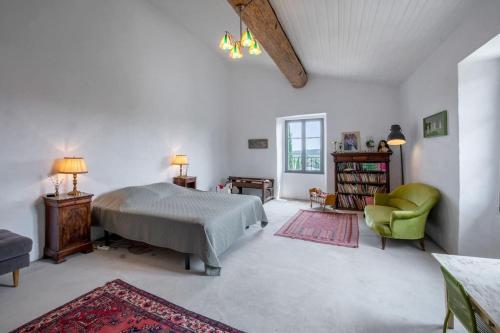 a bedroom with a bed and a green chair at Mas Carpe Diem avec piscine privée et wifi in Orthoux-Sérignac-et-Quilhan