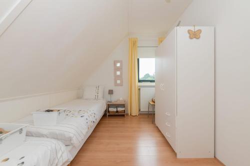 a white bedroom with two beds and a window at Duynopgangh 25 in Julianadorp