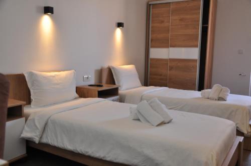 two beds in a hotel room with white sheets at Nego apartmani in Kuršumlija