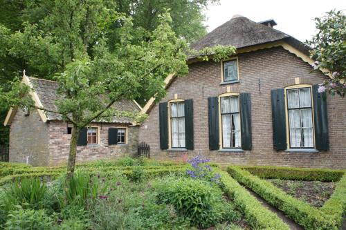 een oud bakstenen huis met zwarte ramen en een tuin bij Blokhut in Putten