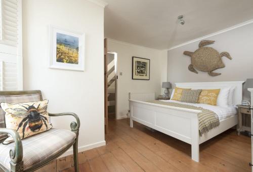a bedroom with a white bed and a chair at Tathra Beach Cottage in St Ives
