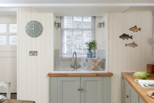 a kitchen with a sink and a clock on the wall at Tathra Beach Cottage in St Ives