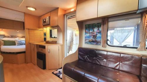 a living room with a kitchen and a bedroom in an rv at Maliblues Bed & Art Gallery in Chumphon