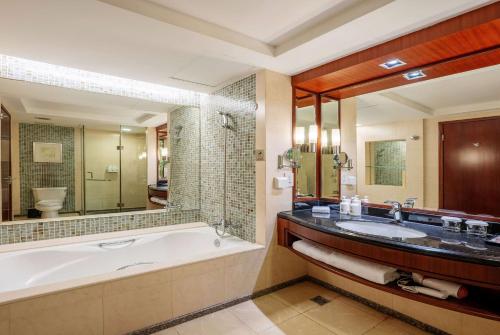 a bathroom with a tub and a large mirror at Ramada Beijing North in Changping