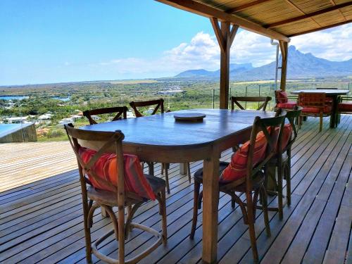 a wooden table and chairs on a deck with a view at Villa Teranga avec vue panoramique sur la baie de Tamarin in Tamarin