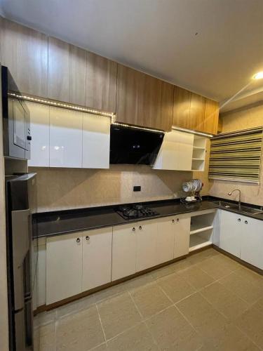 a kitchen with white cabinets and stainless steel appliances at All States Apartments in Abuja