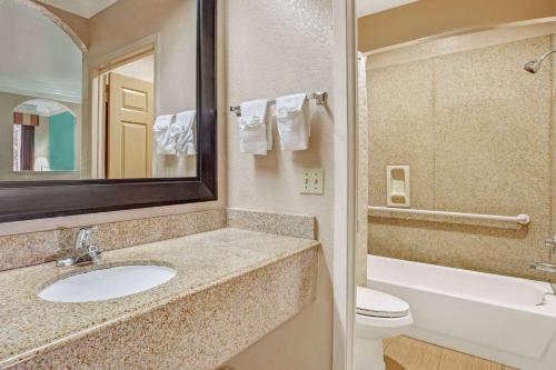 y baño con lavabo, aseo y espejo. en Super 8 by Wyndham Galveston en Galveston