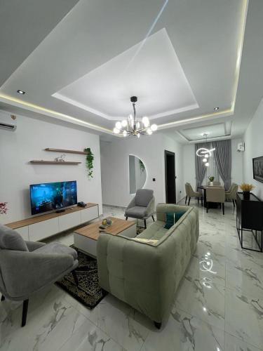 - un salon avec un canapé, des chaises et une télévision dans l'établissement All States Apartments, à Abuja