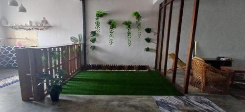 a living room with a green floor with plants at Cozy Nature Homestay - Free Wifi Disney Hotstar ADS in Nibung Tebal