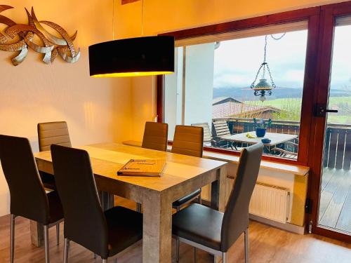 a dining room table and chairs with a view of a balcony at Bungalow am Fuße der Wasserkuppe in Dipperz