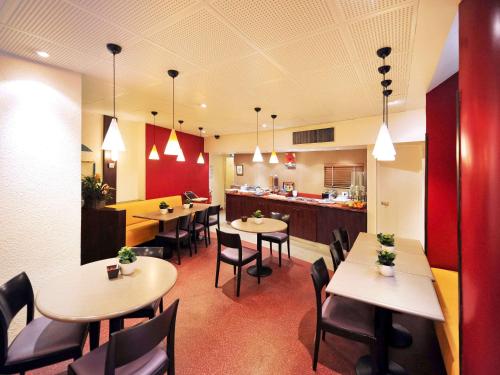 un restaurant avec des tables et des chaises et une cuisine dans l'établissement Ibis Paris Gare Montparnasse 15ème, à Paris