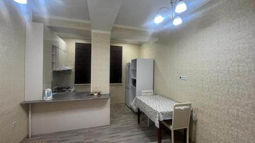 Zimmer mit einer Küche mit einem Tisch und einem Kühlschrank. in der Unterkunft Апарт отель Гок Таш in Bischkek