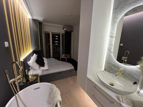 y baño con cama, lavabo y espejo. en VipWarsawApartments pl Gold Mennica Residence, en Varsovia
