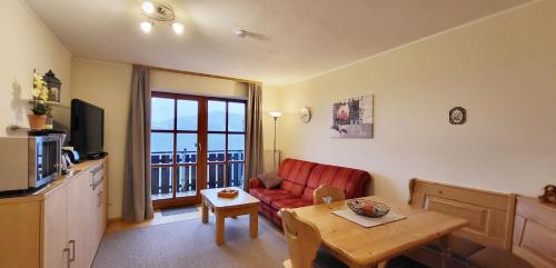 ein Wohnzimmer mit einem roten Sofa und einem Tisch in der Unterkunft Appartement Hauzenberg-Panorama in Hauzenberg