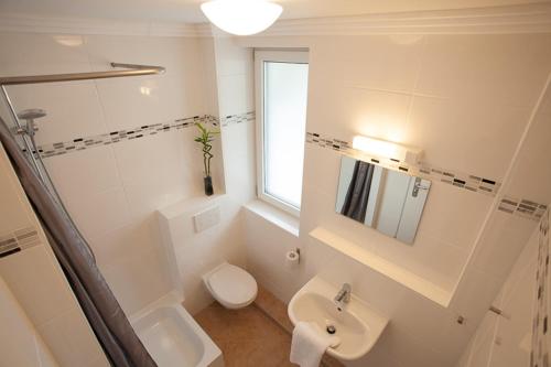 Baño blanco con lavabo y aseo en guenstigschlafen24 – die günstige Alternative zum Hotel, en Múnich