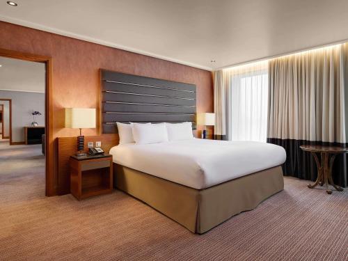 a large bedroom with a large bed and a desk at Sofitel London Heathrow in Hillingdon