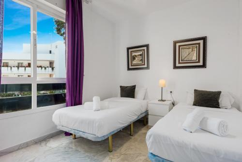 two beds in a room with a window at Great 2-Bed Apartment in Nueva Andalucia Marbella in Marbella