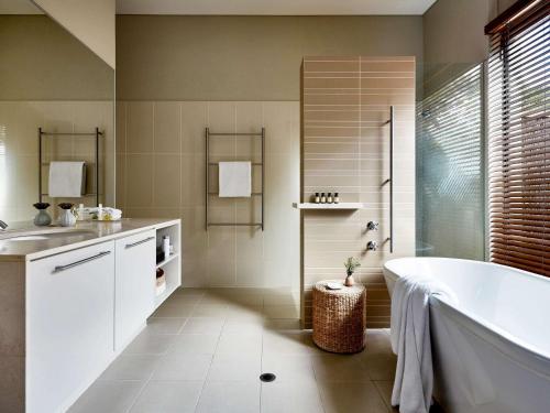 a bathroom with a tub and a sink at Pullman Bunker Bay Resort Margaret River in Dunsborough