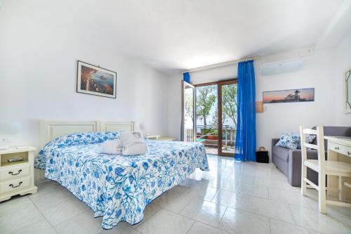 Schlafzimmer mit einem Bett mit einer blauen und weißen Bettdecke in der Unterkunft Punta Chiarito Resort in Ischia