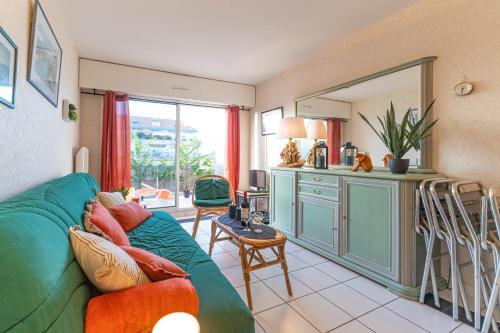 un salon avec un canapé vert et une cuisine dans l'établissement Heliodore - Appartement terrasse vue Bassin, à Arcachon