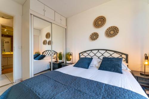 une chambre avec un grand lit avec des oreillers bleus dans l'établissement Heliodore - Appartement terrasse vue Bassin, à Arcachon