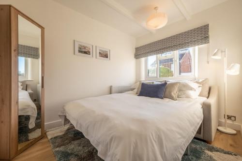 ein Schlafzimmer mit einem großen weißen Bett und einem Spiegel in der Unterkunft Golf Cottage in West Runton