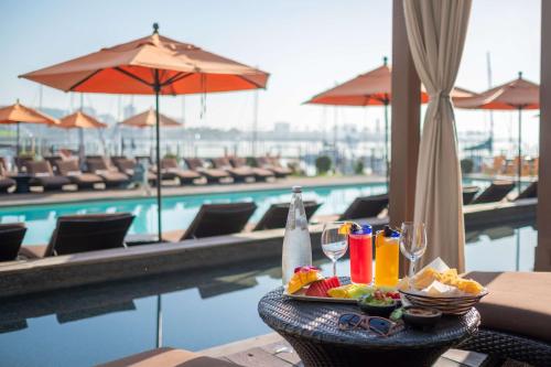 a table with a tray of food and drinks next to a pool at Hotel Maya - a DoubleTree by Hilton Hotel in Long Beach