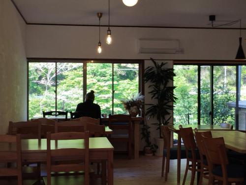 a person sitting at a table in a restaurant looking out the window at そらやまゲストハウス Sorayama guesthouse in Ino