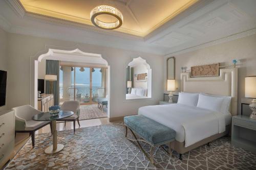 um quarto com uma grande cama branca e uma secretária em Waldorf Astoria Ras Al Khaimah em Ras al-Khaimah