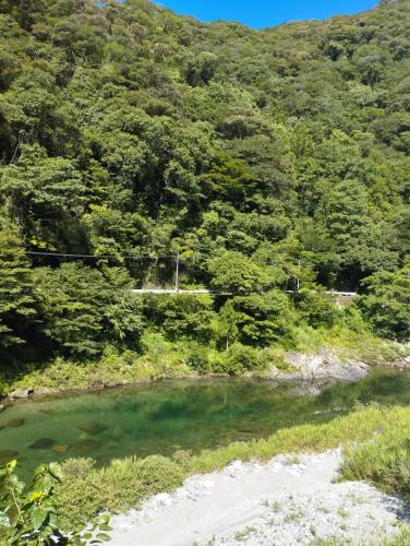 a river in the middle of a mountain with trees at そらやまゲストハウス Sorayama guesthouse in Ino