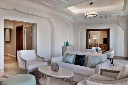 a living room with a white couch and chairs at Waldorf Astoria Ras Al Khaimah in Ras al Khaimah