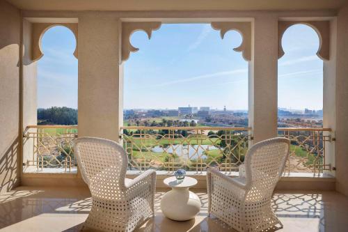 a balcony with chairs and a table with a view at Waldorf Astoria Ras Al Khaimah in Ras al Khaimah