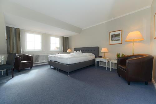 a bedroom with a bed and a desk and chairs at Kurhaus Hotel in Wyk auf Föhr