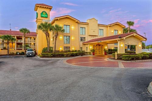 un grand bâtiment jaune avec une tour d'horloge dans un parking dans l'établissement La Quinta Inn by Wyndham Orlando Airport West, à Orlando