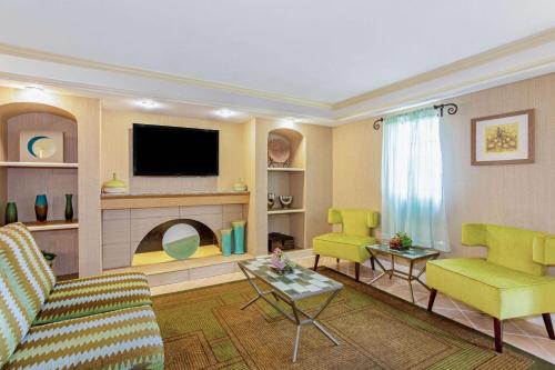 a living room with a couch and chairs and a tv at La Quinta Inn by Wyndham Orlando Airport West in Orlando