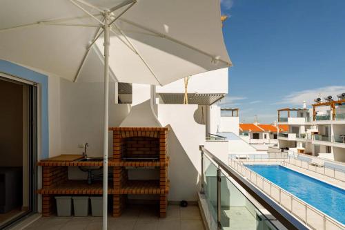 a balcony with an umbrella and a swimming pool at The Albufeira Concierge - Rêve d'été in Vila Nova De Cacela