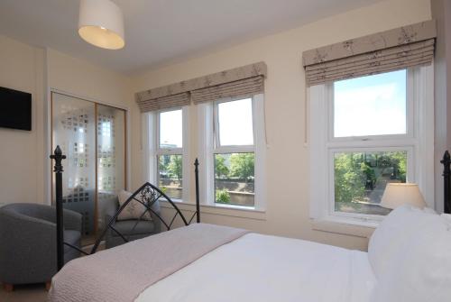 a bedroom with two windows and a bed and a chair at Abbey Guest House York in York