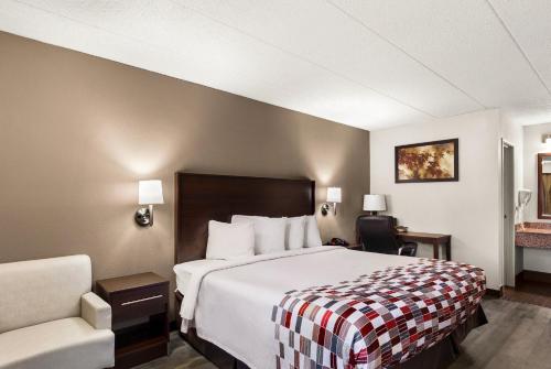 a hotel room with a bed and a chair at Red Roof Inn Springfield, IL in Springfield