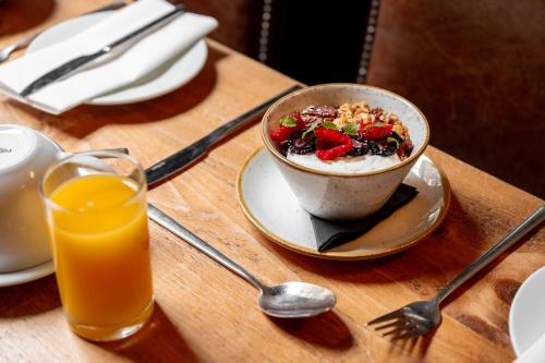 Ein Tisch mit einer Schüssel Müsli und einem Glas Orangensaft in der Unterkunft The Fat Badger in York
