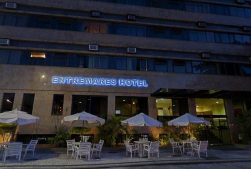 a group of tables with umbrellas in front of a building at Entremares Hotel in Rio de Janeiro