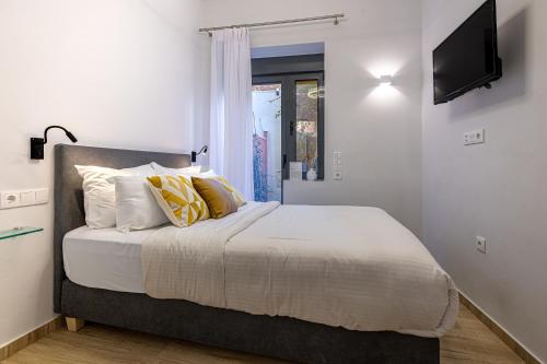 - une chambre avec un lit doté de draps blancs et d'oreillers jaunes dans l'établissement Phaedrus Living: The Nine Muses Polymnia, à Athènes
