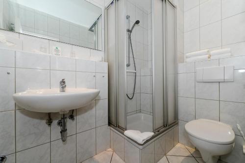 ein Bad mit einer Dusche, einem Waschbecken und einem WC in der Unterkunft Kurhaus Hotel in Wyk auf Föhr