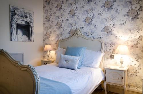 um quarto com uma cama branca e almofadas azuis em The Old House At Home em Castle Combe