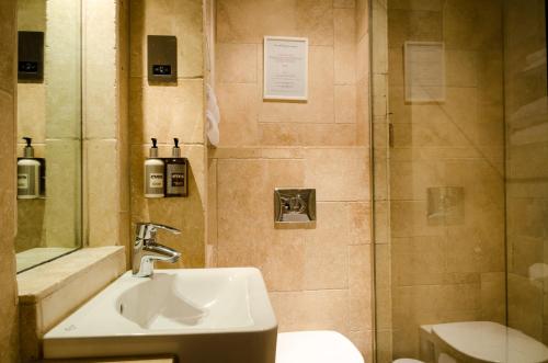 uma casa de banho com um lavatório e um chuveiro em The Old House At Home em Castle Combe