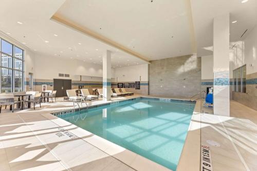 a large swimming pool in a room with a table and chairs at Embassy Suites By Hilton Irving Las Colinas in Irving